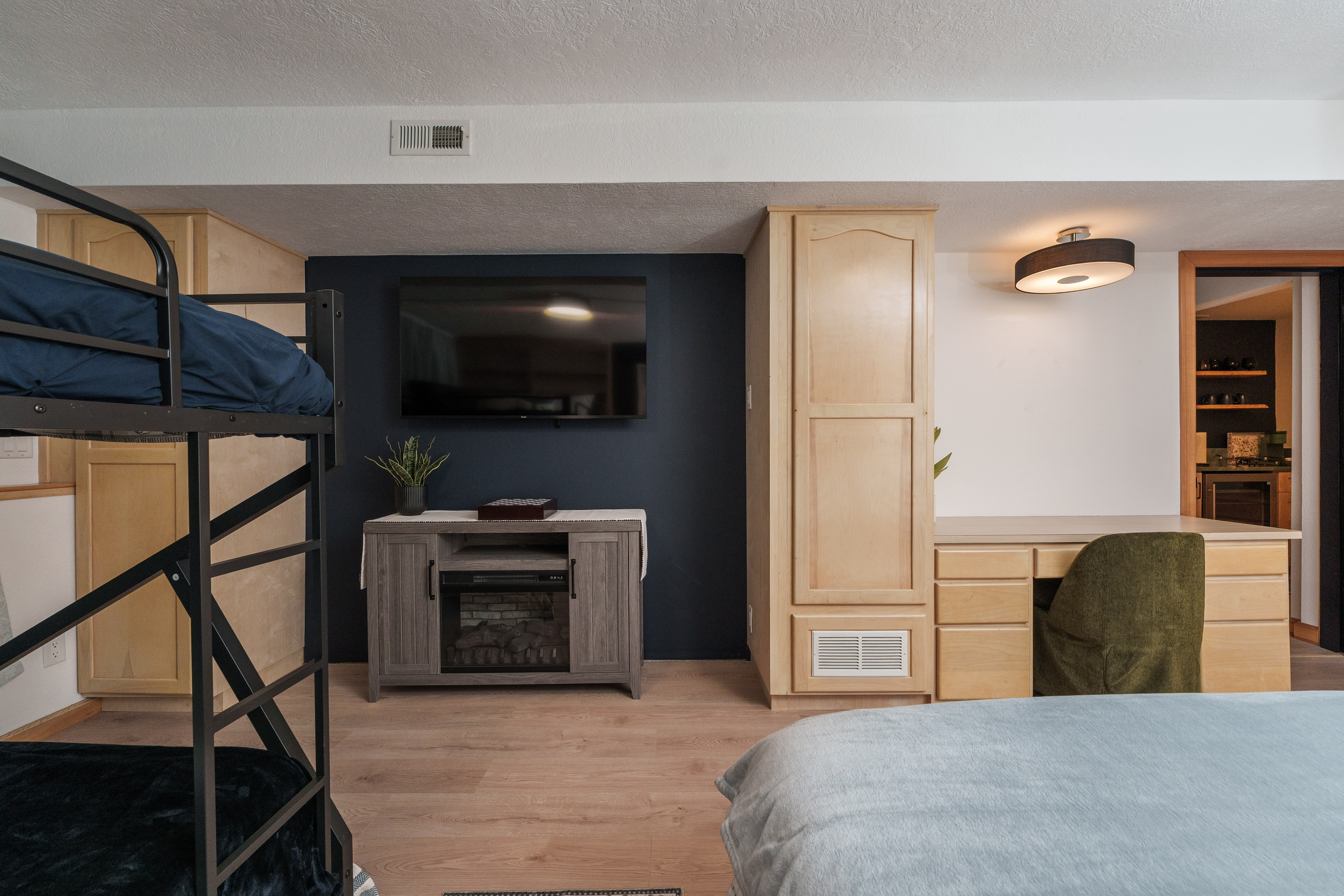 Bedroom 2 is thoughtfully designed for families and groups, featuring a queen bed, a queen-over-queen bunk bed, a dedicated remote-work desk, and a private ensuite bathroom (Bathroom 2)
