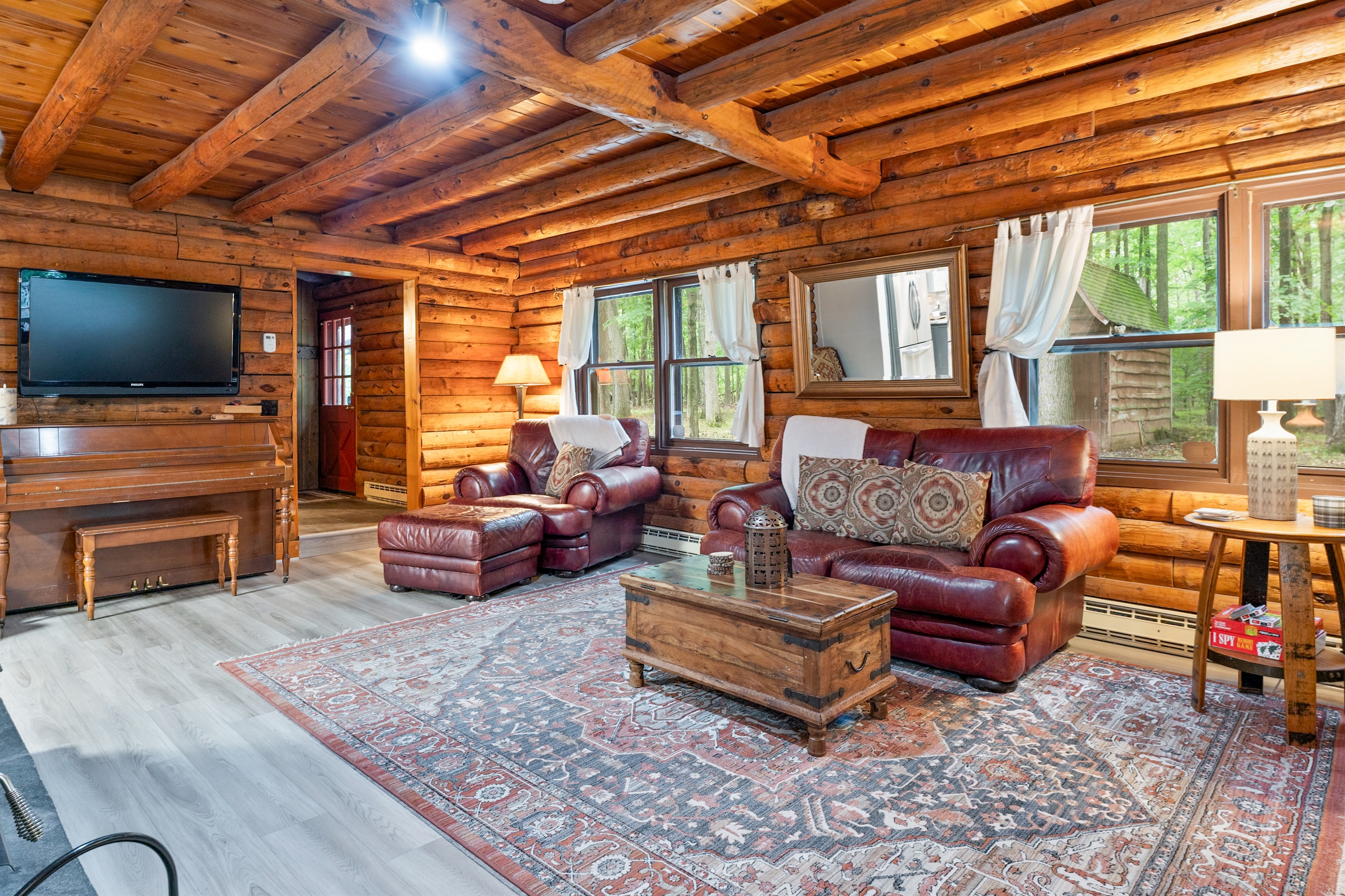 A cozy log cabin living room featuring rich wood beams, leather seating, and natural light pouring through the windows—perfect for relaxing after a day outdoors.