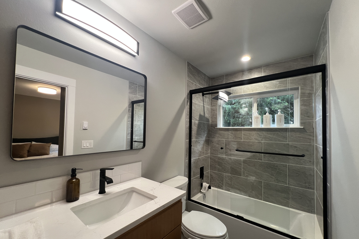 A spa-inspired full bath with a sleek vanity, black fixtures and a shower–tub combo — fresh, modern comfort for a full house.