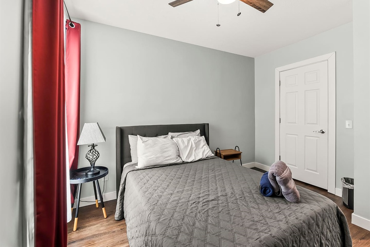 Bright bedroom view with full-size bed, nightstands, and soft natural light from the window.