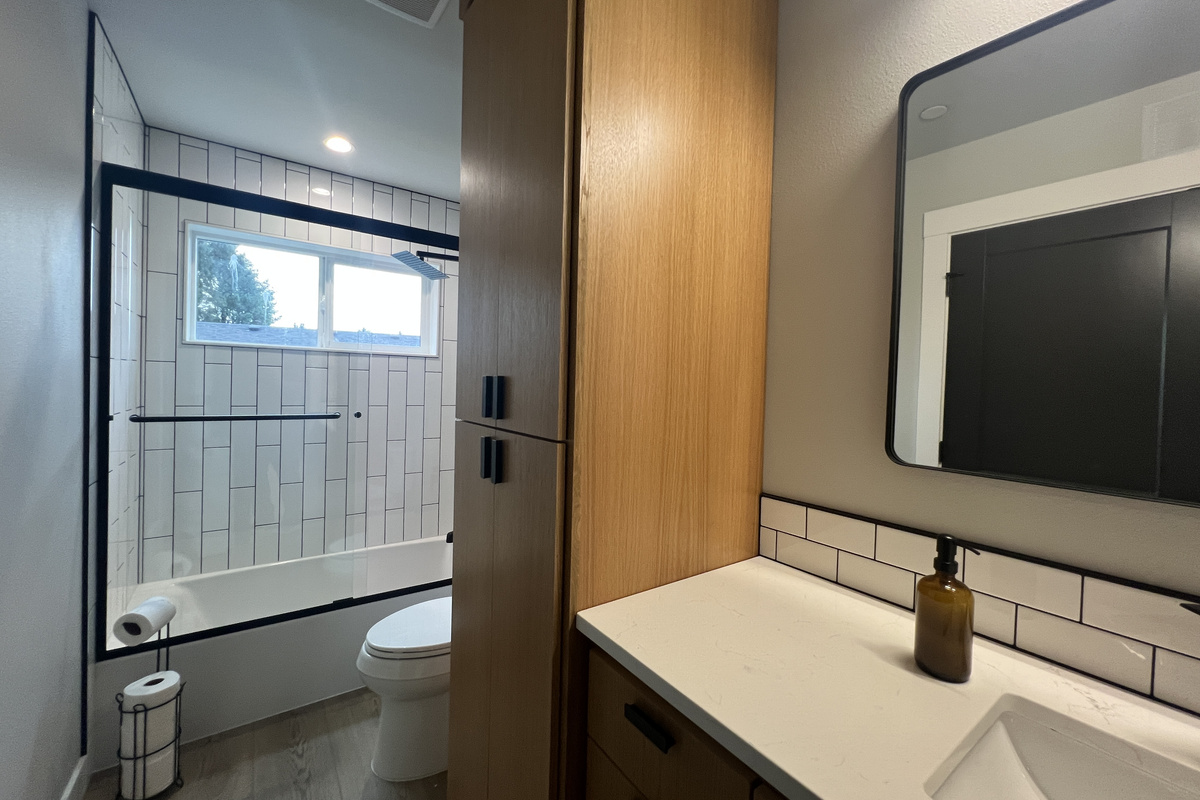 A crisp, modern bathroom with a tiled tub-and-shower combo — fresh, functional and ready for guests.