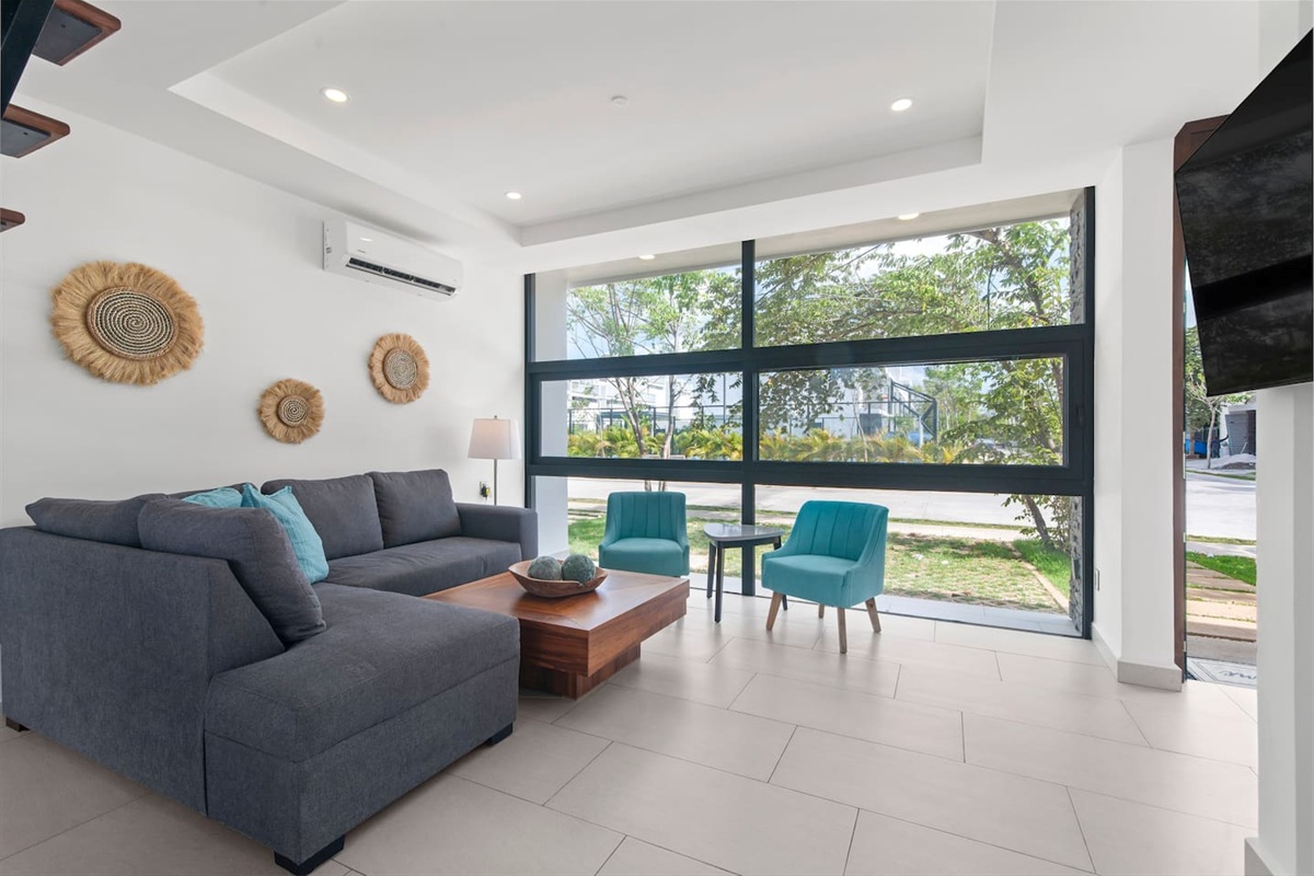 Living space with TV and comfortable couch overlooking the tennis court on the main floor.