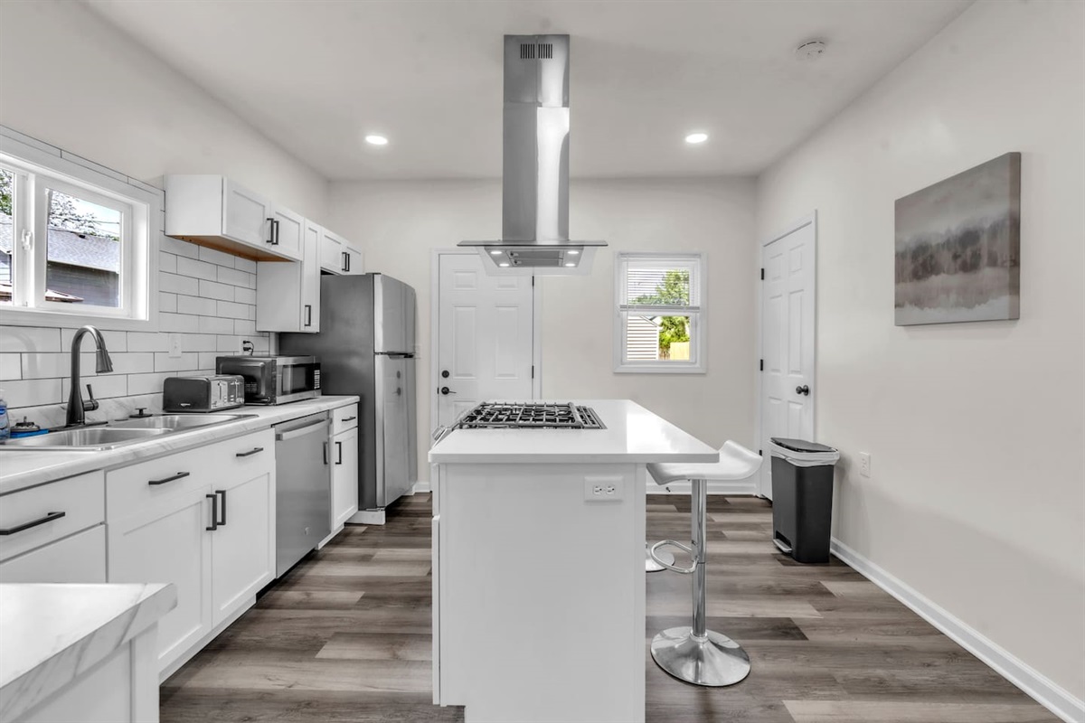 The kitchen boasts an elegant design with a center island featuring a burner, and a fridge, offering both style and practicality.