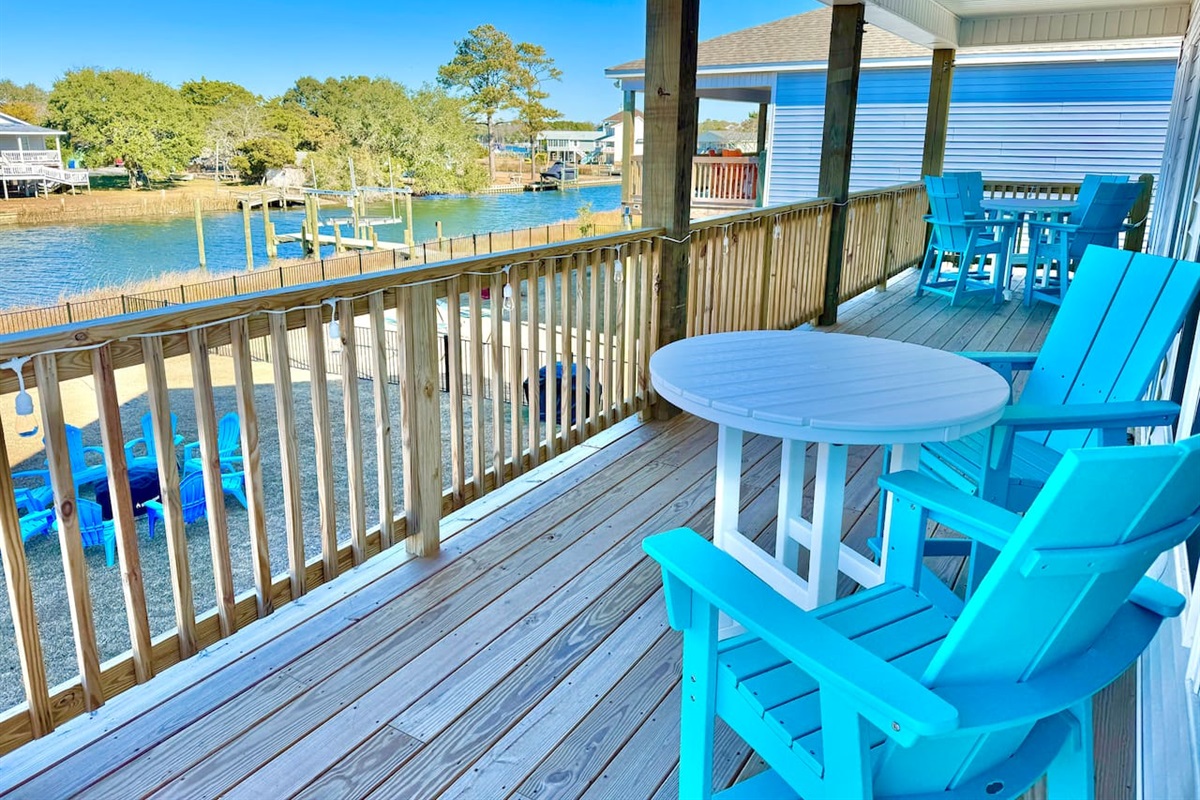 Private backyard dock with boat lift and fillet table, fenced-in backyard, fire pit with Adirondack chairs, hammocks, propane grill, picnic table, outdoor shower, expansive waterfront back deck with string lights, neighborhood boat ramp