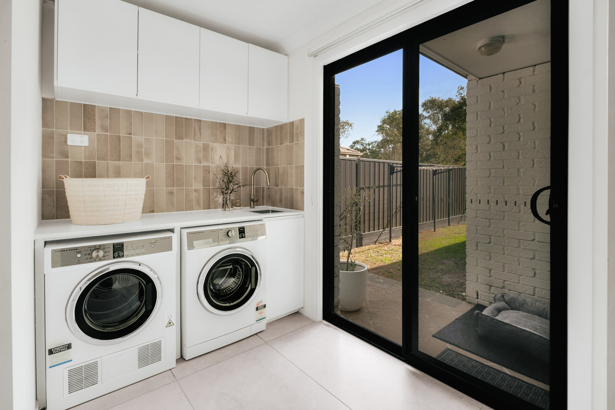 The laundry has a front-load washer, separate dryer and bench space, making everyday washing simple during the stay.
