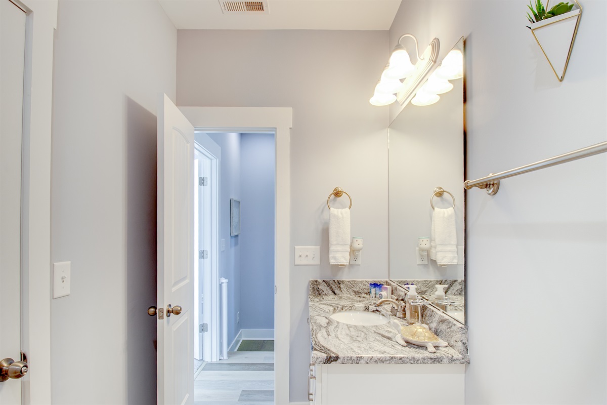 Bright Upstairs bathoom with granite vanity, oversized mirror, and soft coastal finishes.