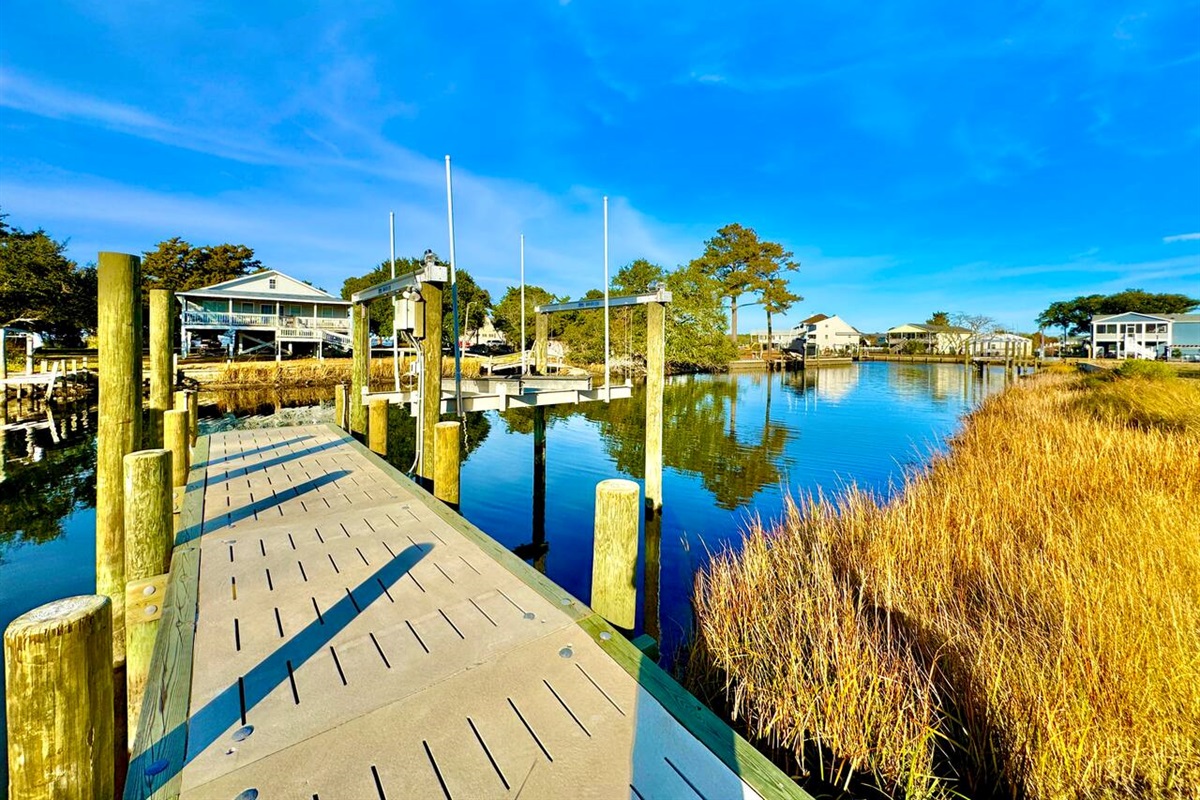 Private backyard dock with boat lift and fillet table, fenced-in backyard, fire pit with Adirondack chairs, hammocks, propane grill, picnic table, outdoor shower, expansive waterfront back deck with table and seating, neighborhood boat ramp and dock