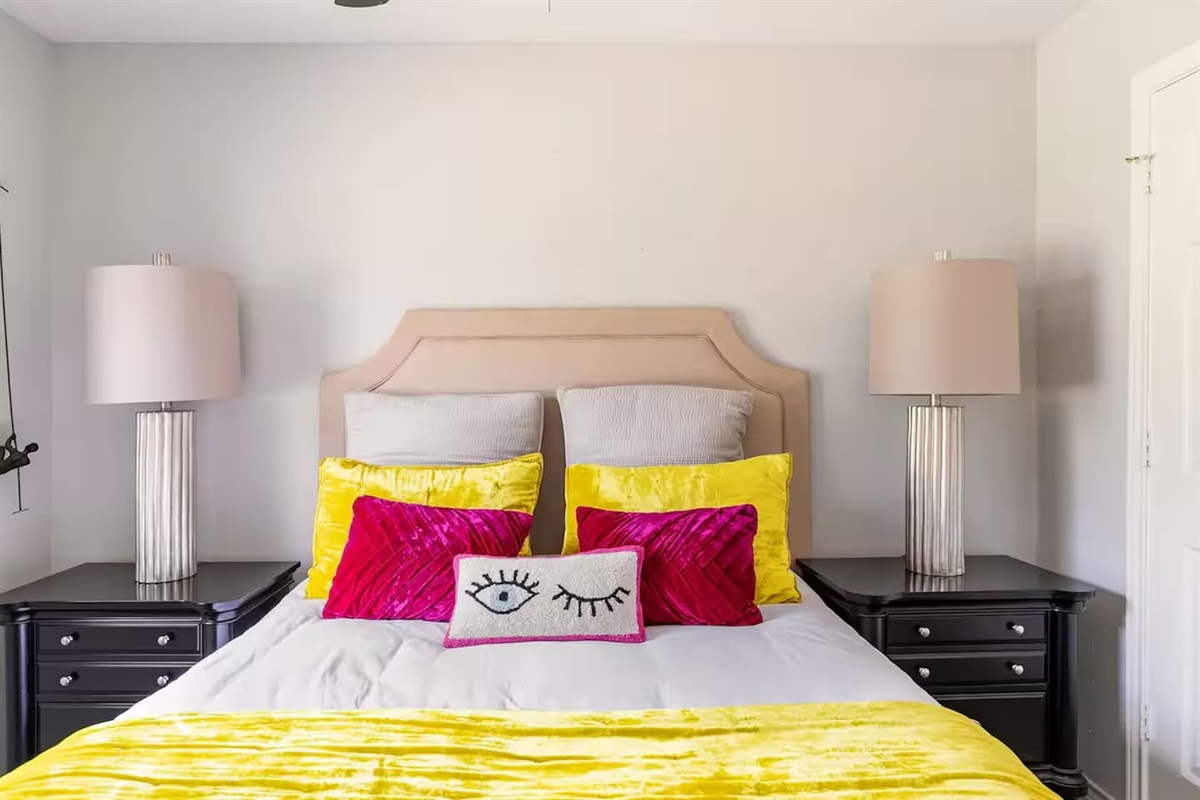 Bedroom with queen bed and colorful accent pillows.
