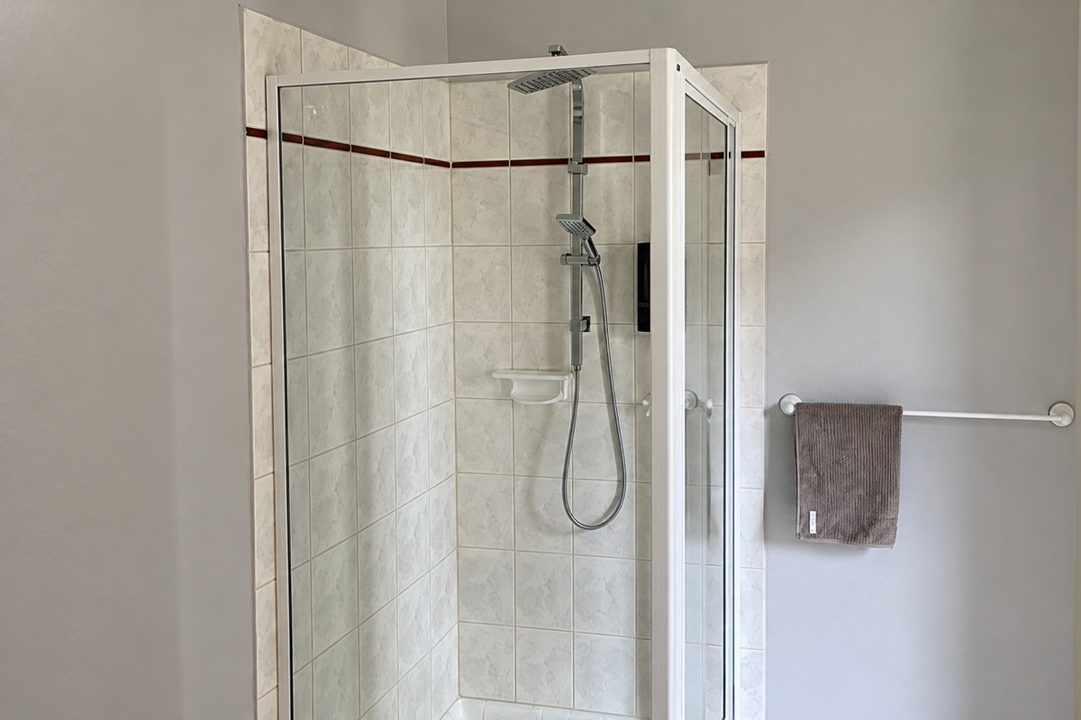 A bright and practical bathroom in the self-contained unit, featuring a spacious shower enclosure and convenient fixtures.