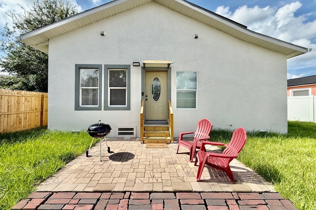 The fully fenced yard offers added privacy, while the red Adirondack chairs and charcoal grill invite you to kick back and savor the moment.