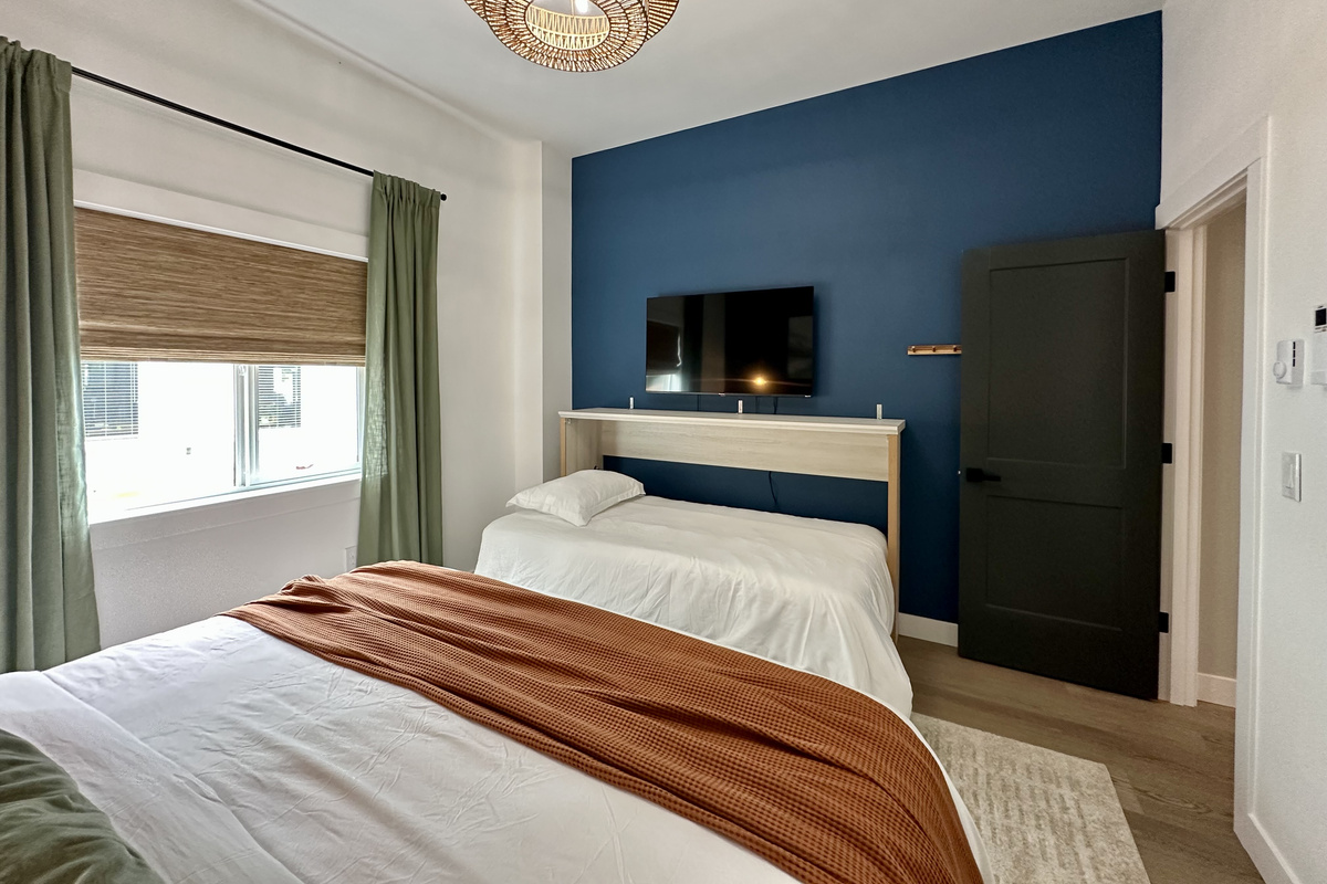 A king bedroom with its own wall-mounted TV, plus a twin alongside for one more sleeper.