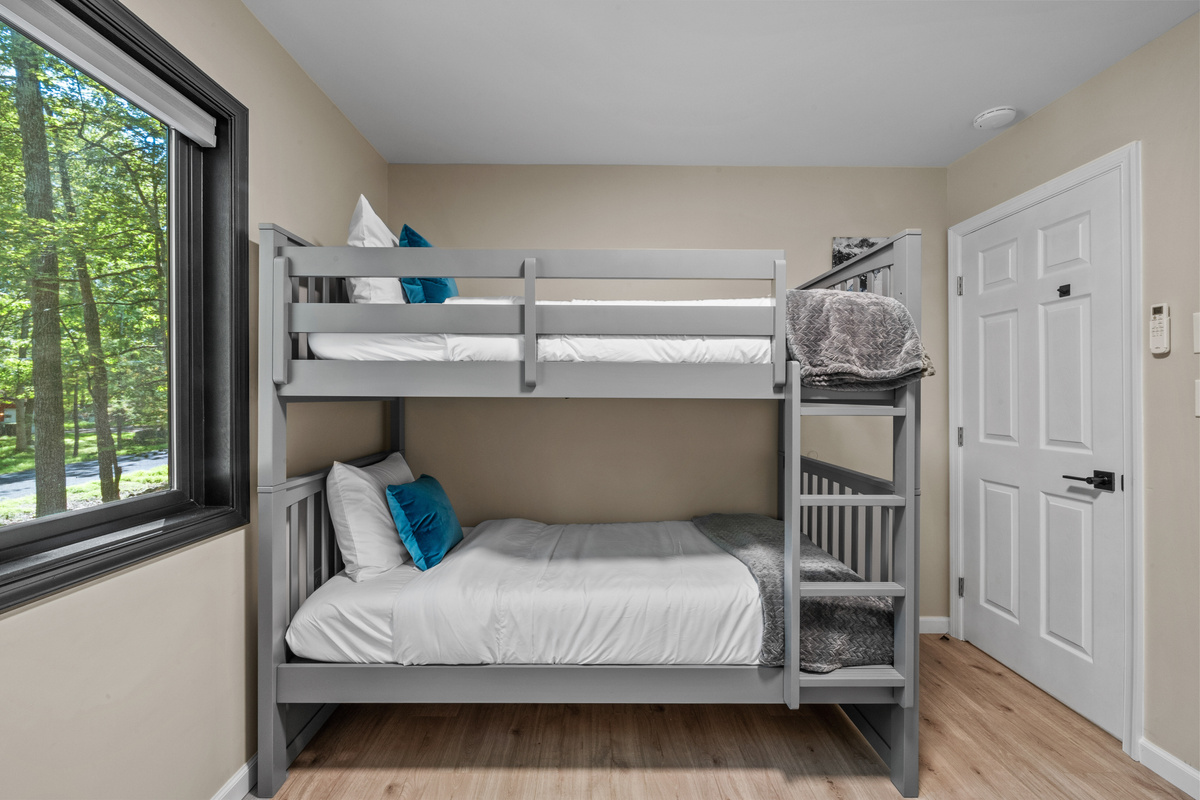 Tall windows let in beautiful glimpses of the surrounding Poconos forest while maintaining a bright yet private bedroom atmosphere.