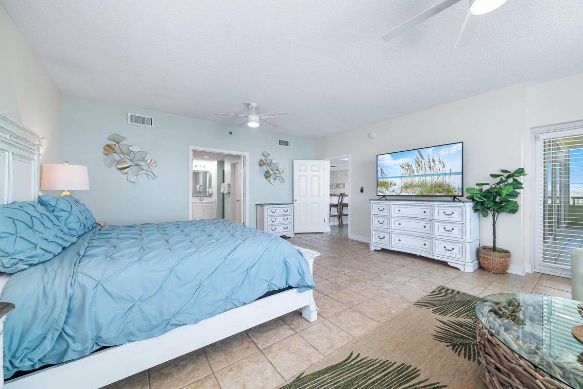 Discover this expansive primary bedroom featuring a King-sized bed with soothing color palette, unique wall art, and direct access to a private ensuite bathroom.