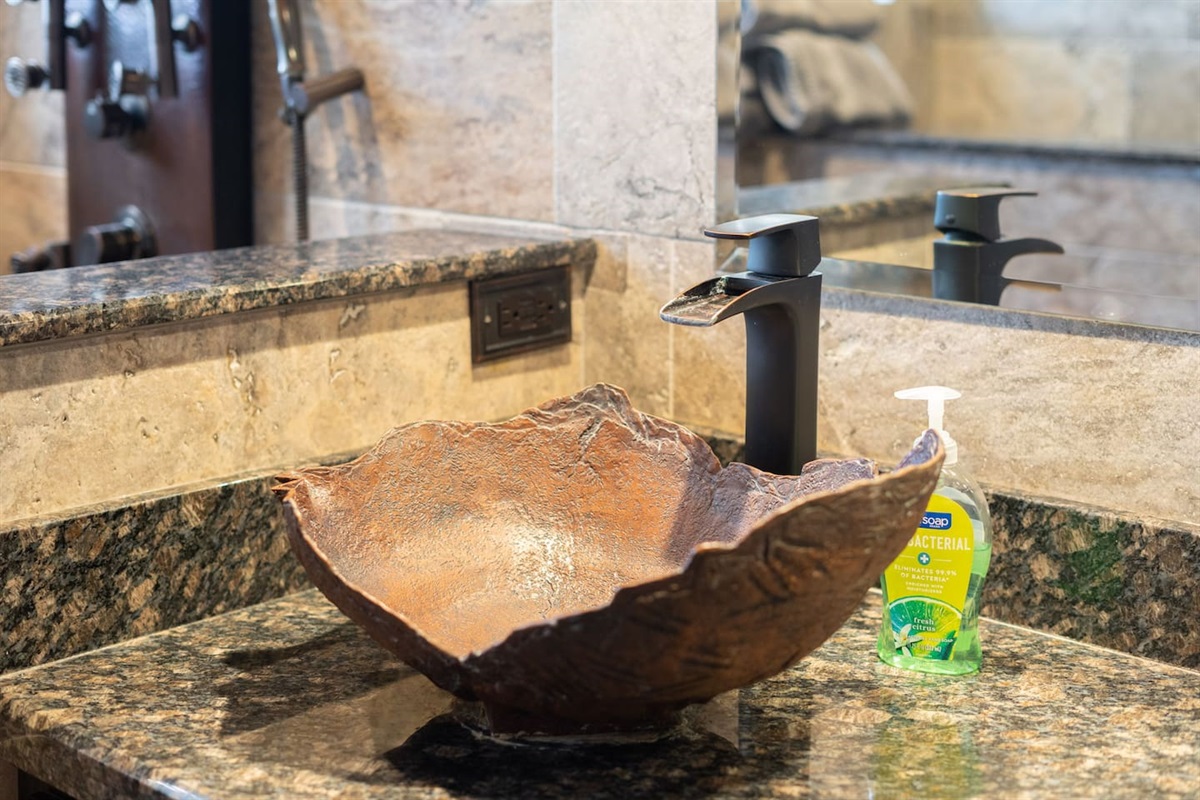 The hand-hammered copper vessel sink is a work of art in itself — paired with a sleek matte black faucet and granite counter, it's the kind of detail that makes guests stop and look twice.