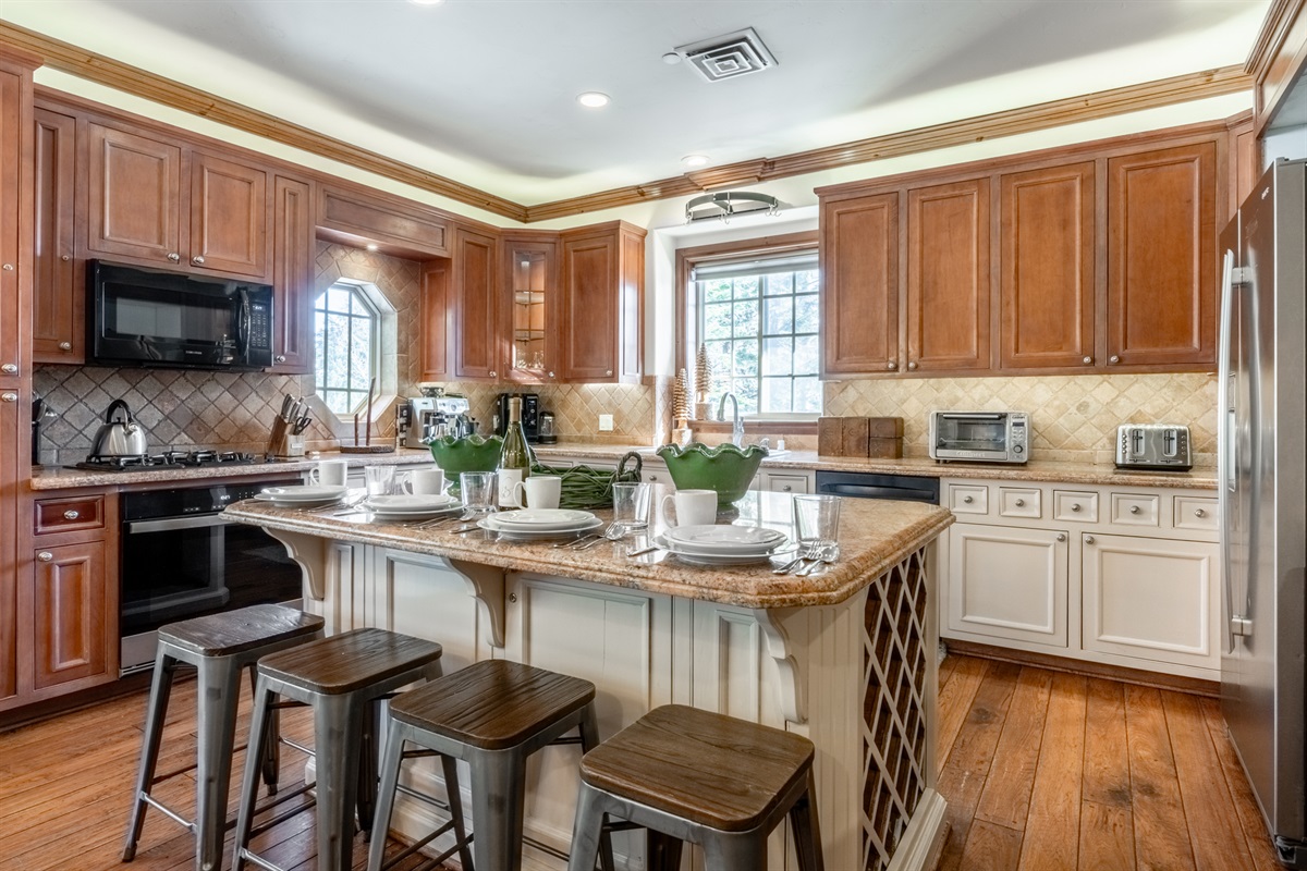 Warm wood finishes, a large island with seating, and abundant natural light create an inviting space in the well-eqipped kitchen.