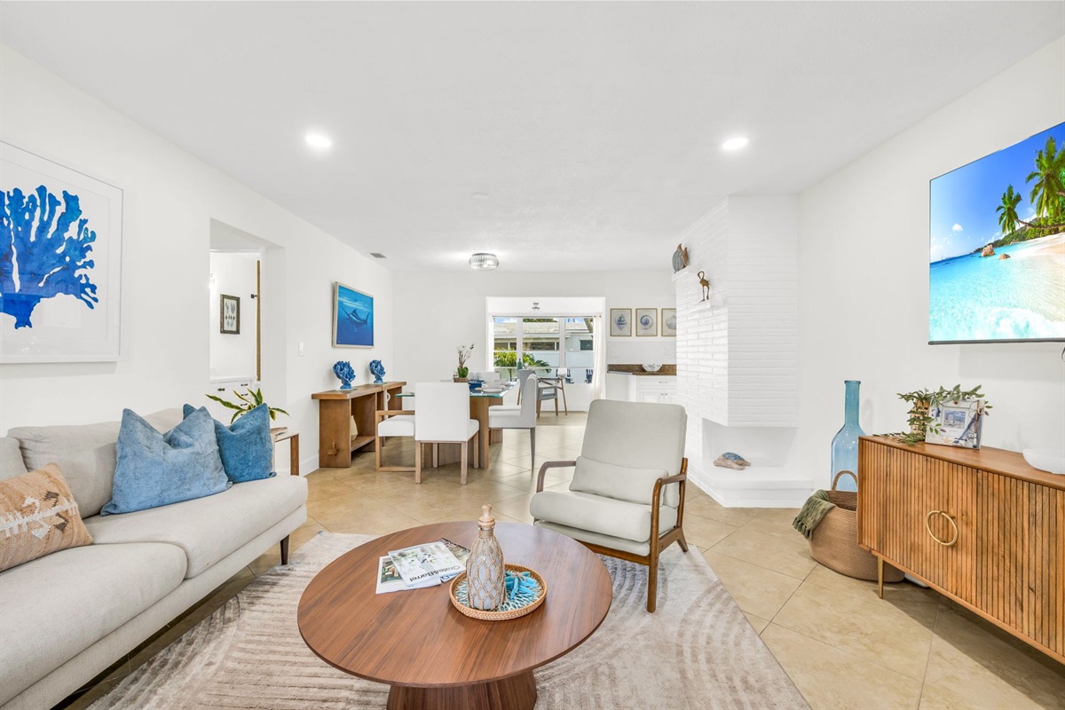 Bright and coastal-inspired, the living room features a plush sofa, stylish accent seating, a large Smart TV, and soothing ocean-toned décor—perfect for relaxing after a day at the beach.