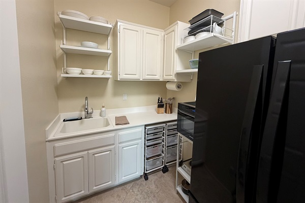 Clean and functional kitchenette with sink, counter space, and full-size refrigerator