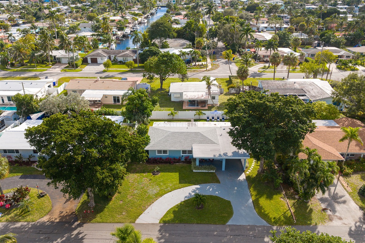 Soaring aerial perspectives highlight the home’s tranquil Pompano Beach neighborhood, private backyard oasis, covered carport, and extended driveway with space for 3 cars.