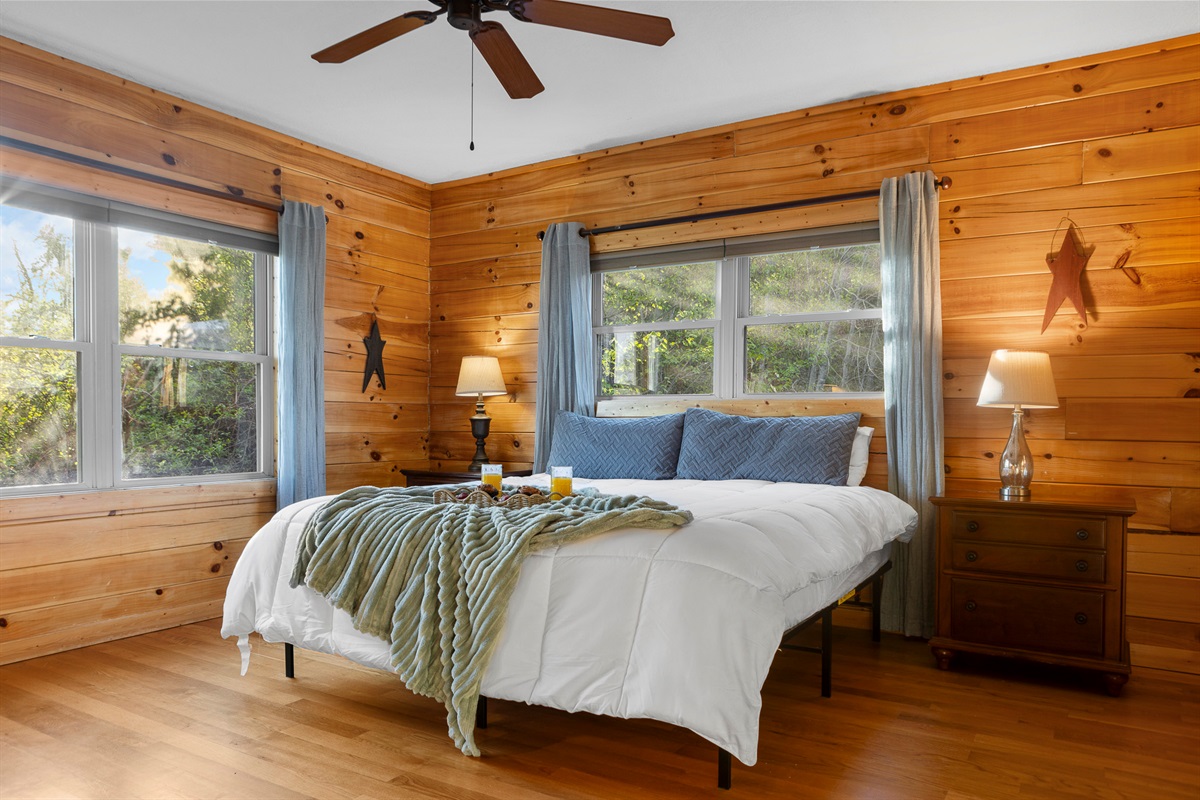Bedroom Retreat: Bright, wood-paneled haven with plush bedding and scenic views to inspire relaxation!

