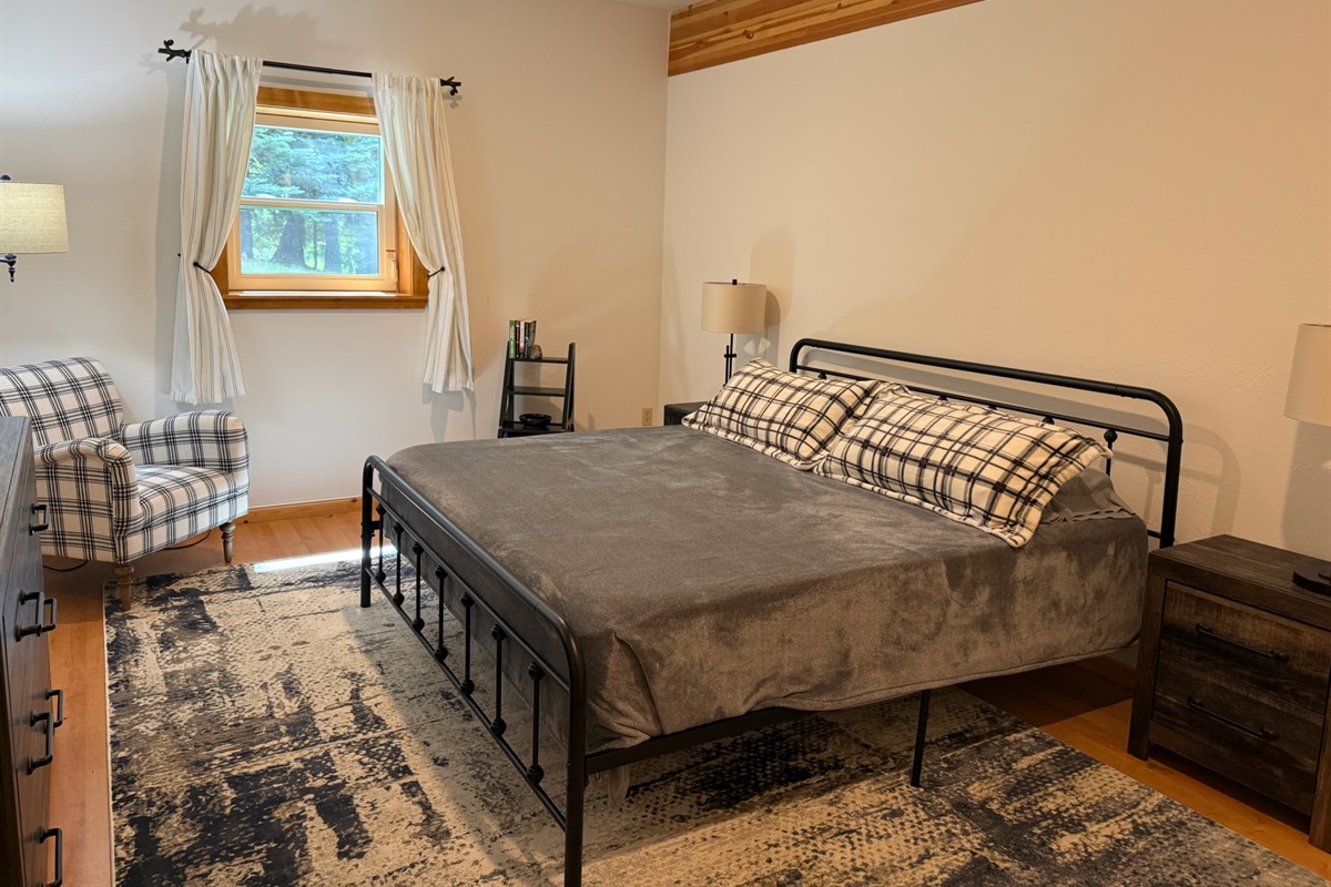 Downstairs guest room with King bed and sitting chair, view to lake and yard