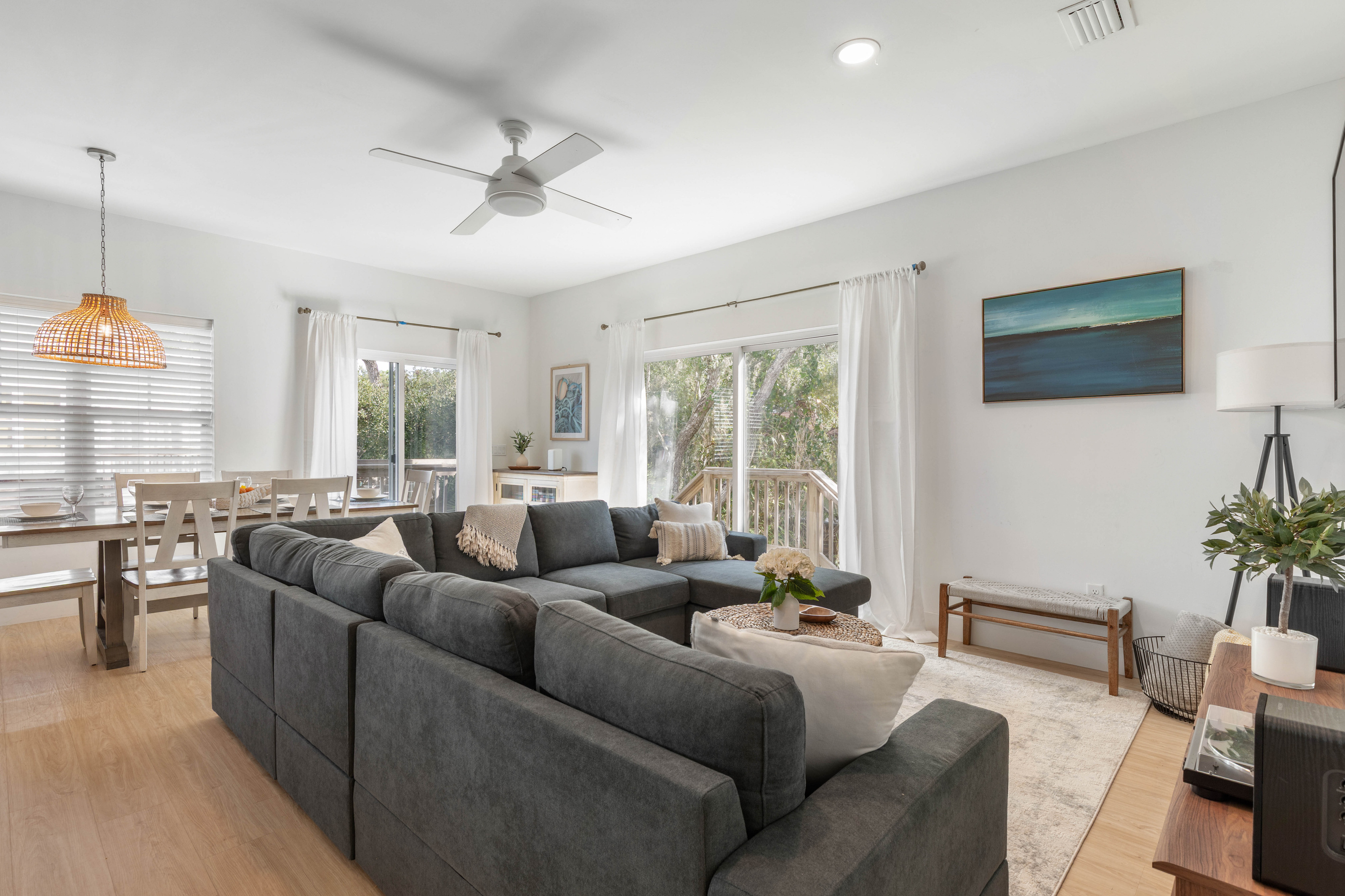 One long room holds the sofa, the table and the doors out to the deck. Someone is always coming through with a towel or a drink, and the sectional runs deep enough that nobody has to fight for the good seat.