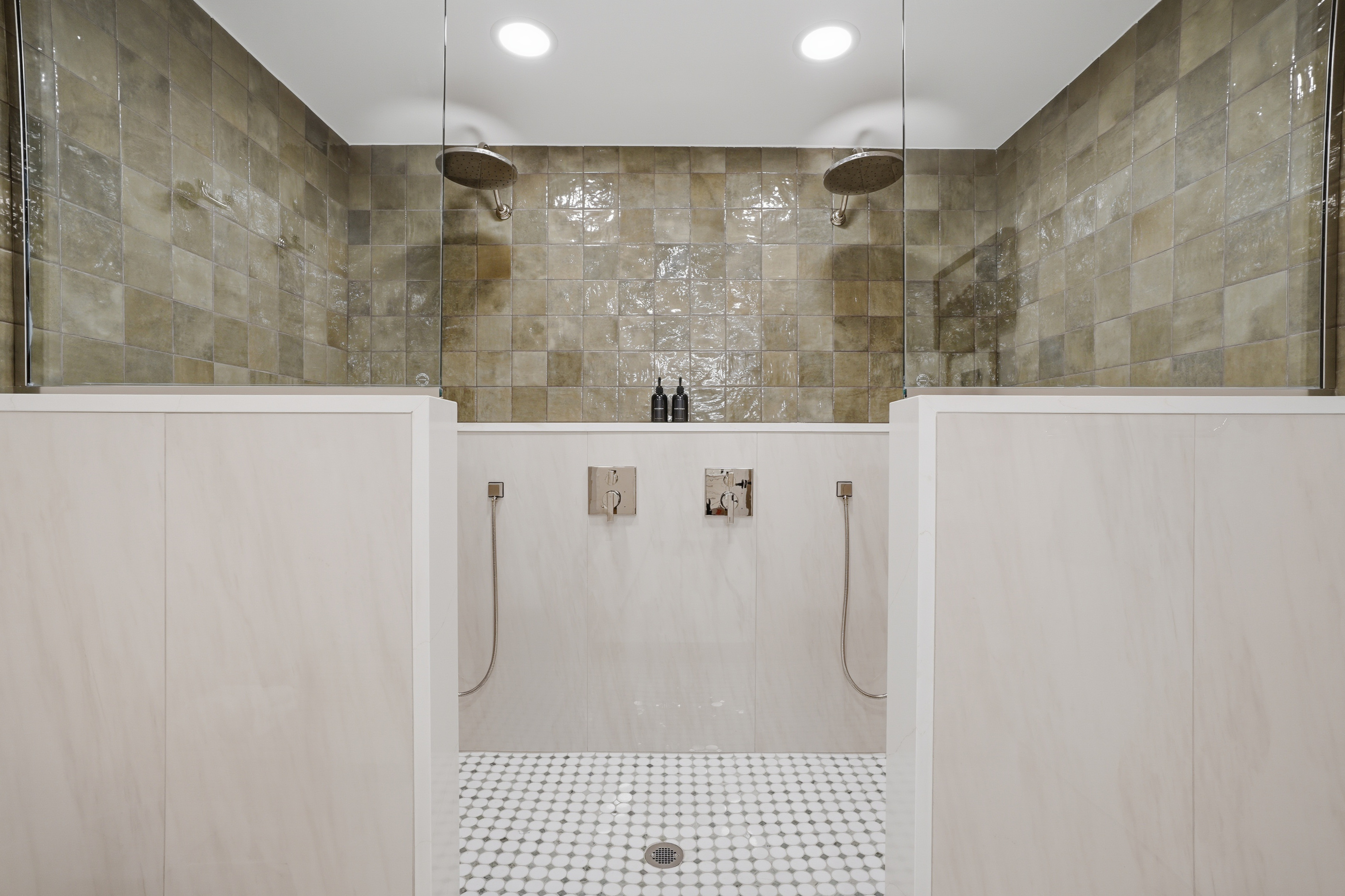 Spa-inspired dual shower area featuring elegant stone tile walls, a sleek glass divider, and a clean, modern layout. Bright, minimalist design with a calm, hotel-like feel for a refreshing and relaxing experience.