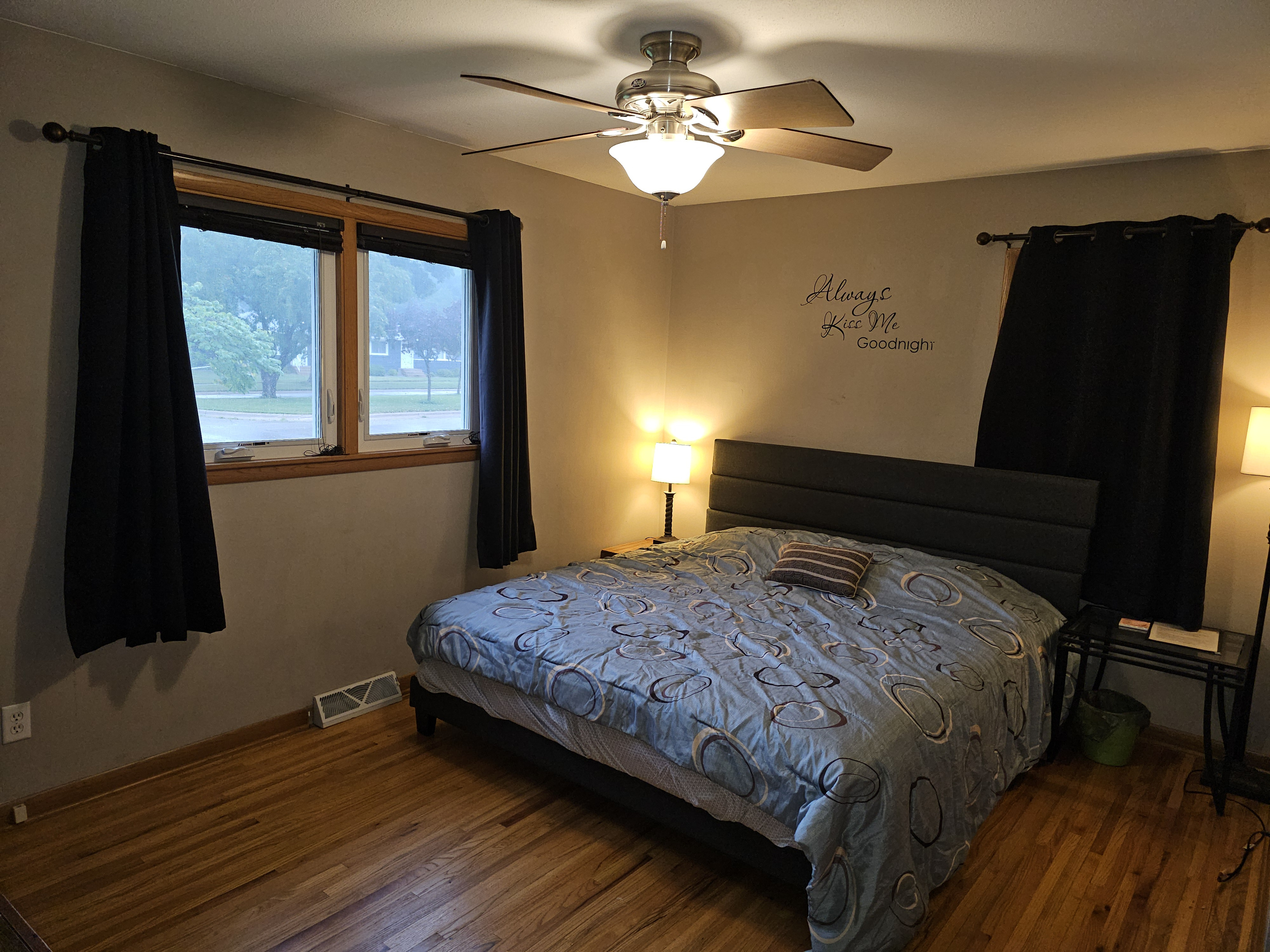 Master bedroom on the main floor with king bed, ceiling fan, alarm clock and a smart tv.