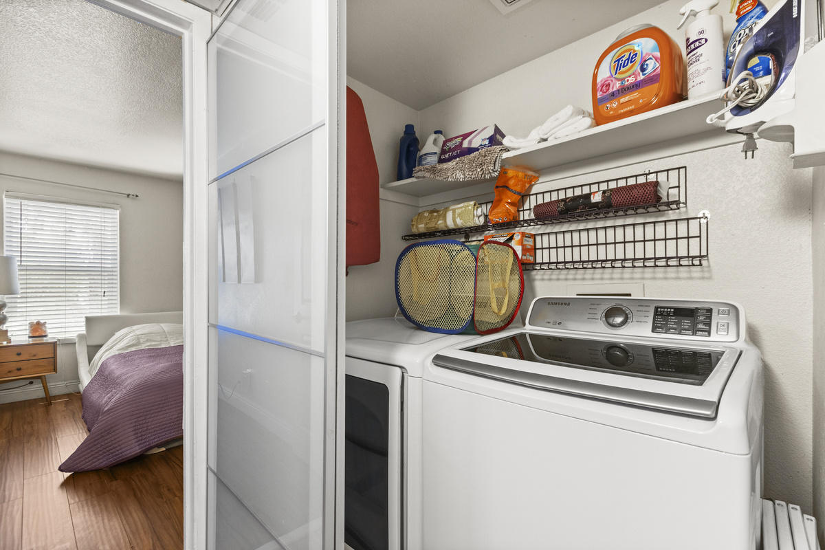 Laundry closet with washer, dryer, and shelves stocked with detergent and cleaning supplies.
