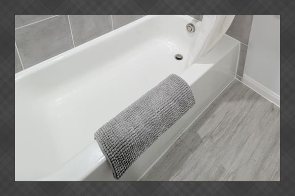 Full tub/shower combo with fluffy towels and bath mat. 