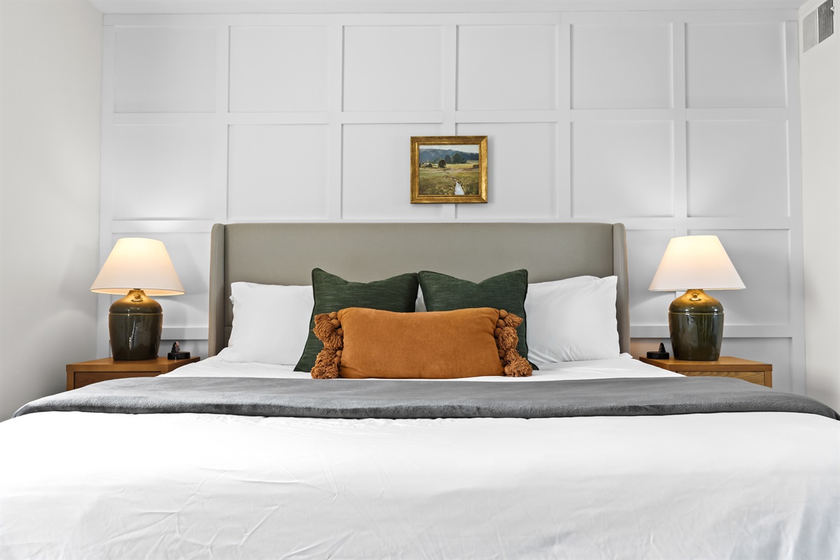Cozy bed with accent pillows and stylish wall paneling.