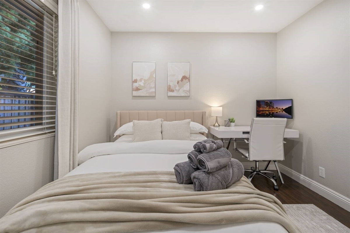 This bedroom workspace includes a sleek desk with a laptop monitor, providing an efficient setup for work or study. An ergonomic office chair adds comfort & support, making this corner both functional & stylish, perfect for a productive environment.