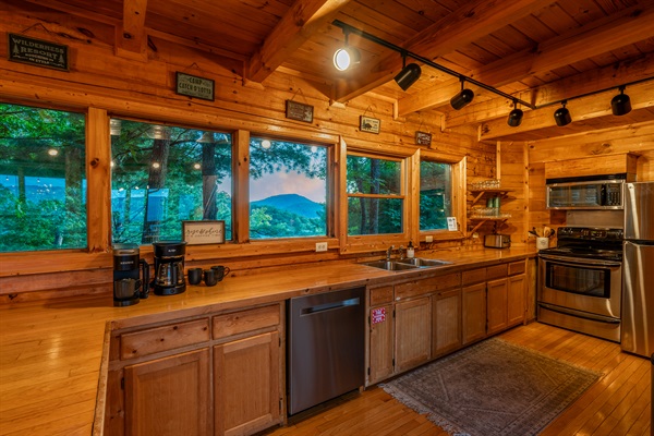 The fully stocked kitchen features a full wall of windows and offers a fridge, freezer, ice maker, oven, stove, microwave, divided sink, and dishwasher