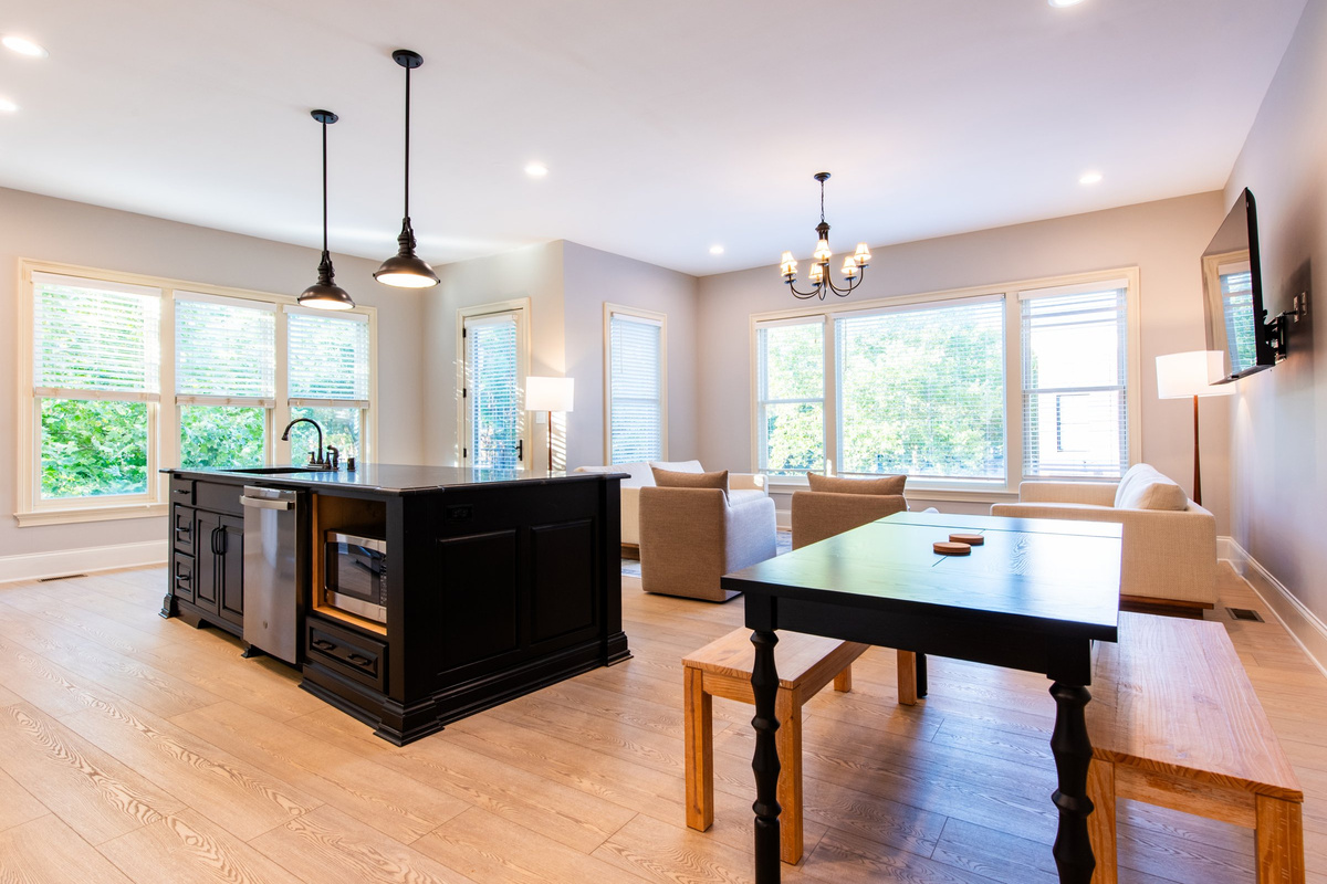 Open-concept living with a custom black island, full kitchen, and a dining table that seats six.
