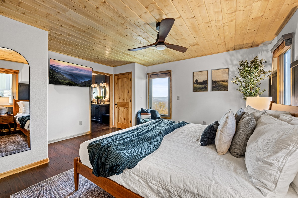Main floor: Unwind in the spacious primary bedroom at Signature Stay, complete with a cozy bed and a TV for your ultimate relaxation
