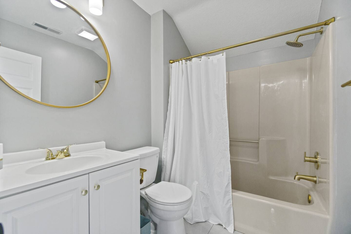 Bright white interior bathroom featuring a sleek sink, stylish mirror, and a modern shower, creating a clean and fresh space.