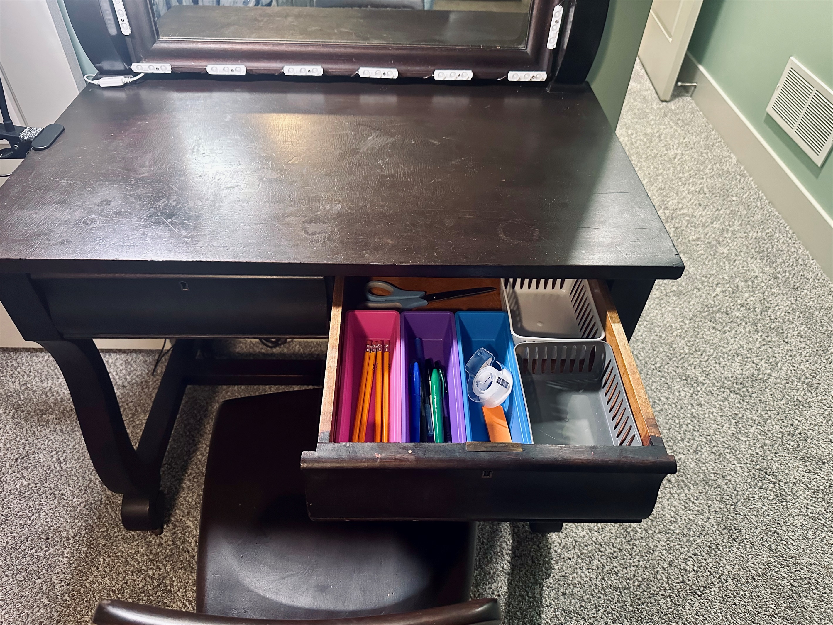 Primary suite desk drawer stocked with essential office supplies including pens, pencils, tape, and scissors for guest use.