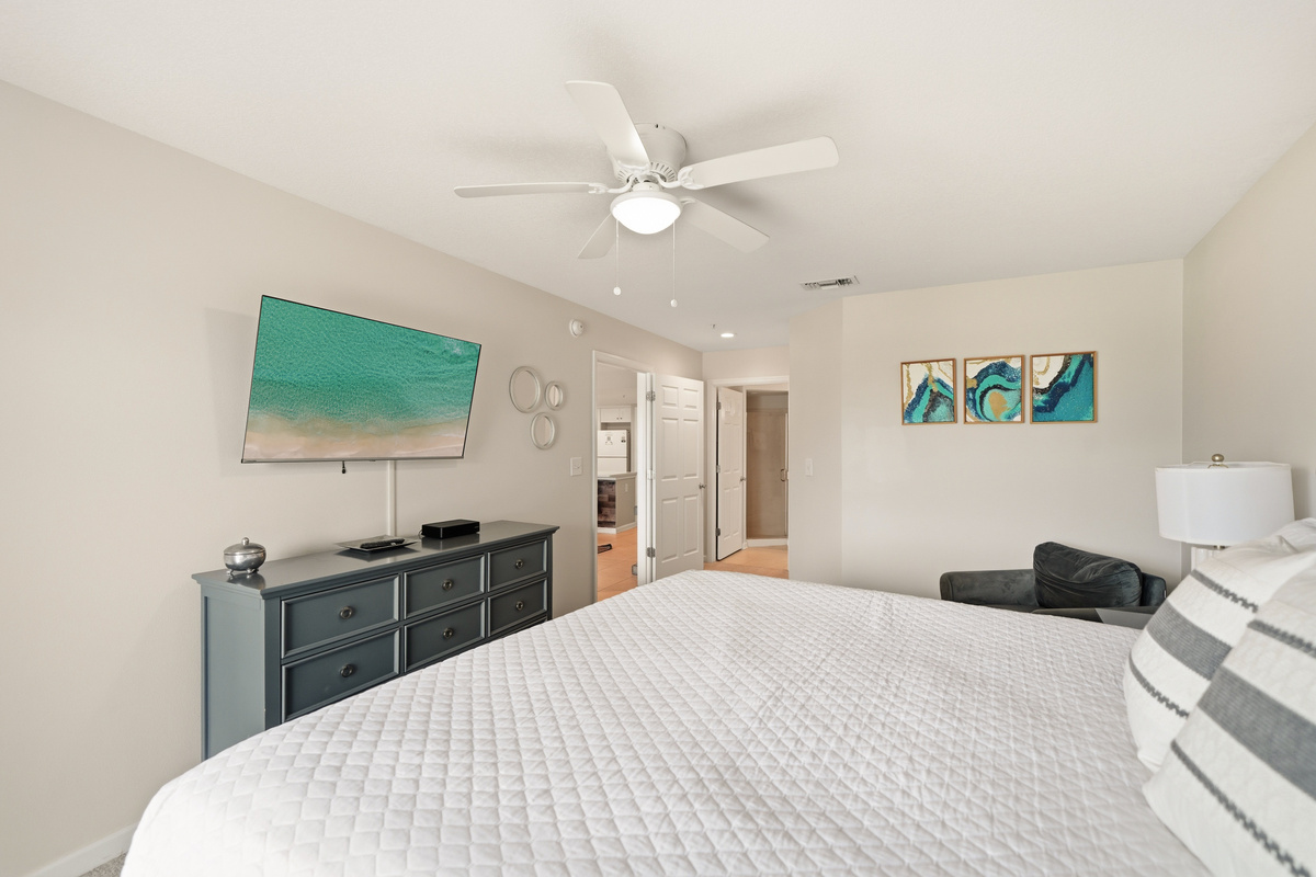 Relax in the comfort of the primary bedroom with a king bed, stylish dresser, and a big screen for unwinding after the beach.