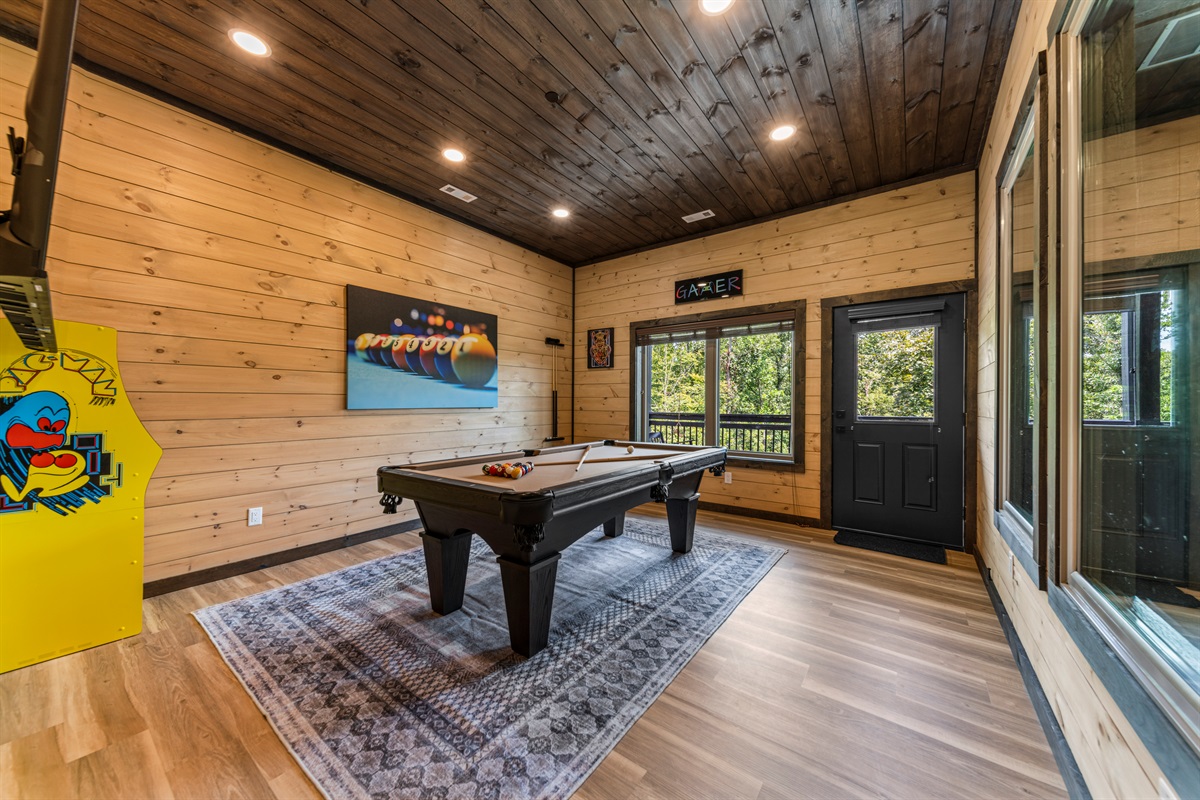 Game room with pool table, arcade machines, and pool view