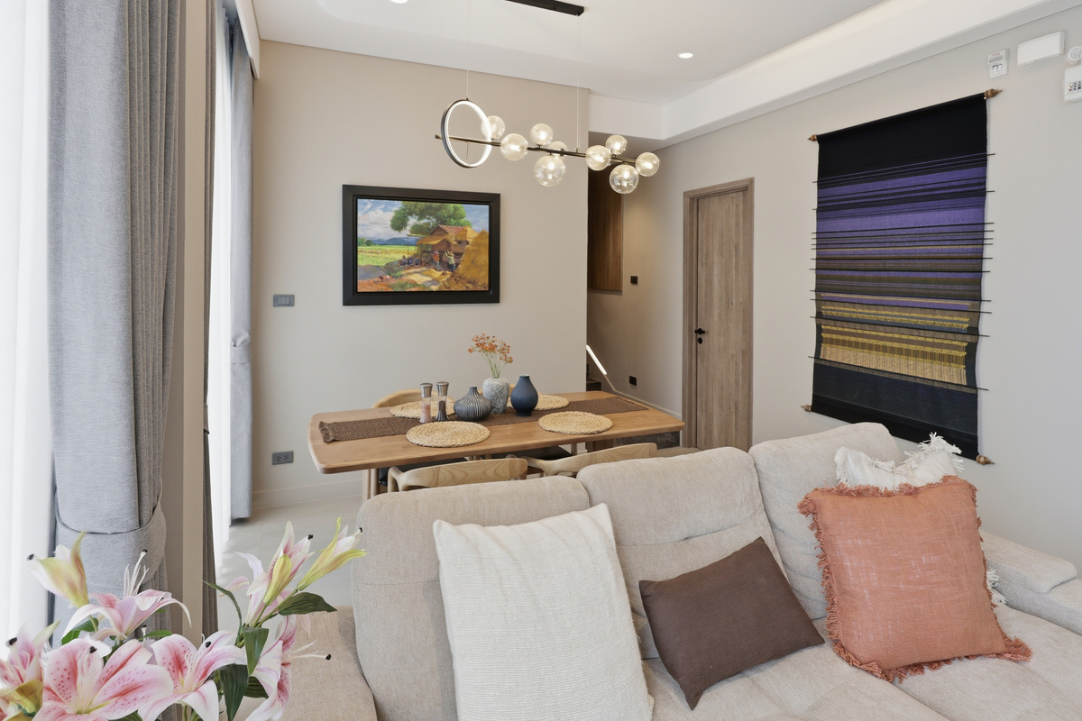 Living room with beige sofa, dining table, framed artwork, pendant lighting, and modern décor throughout.