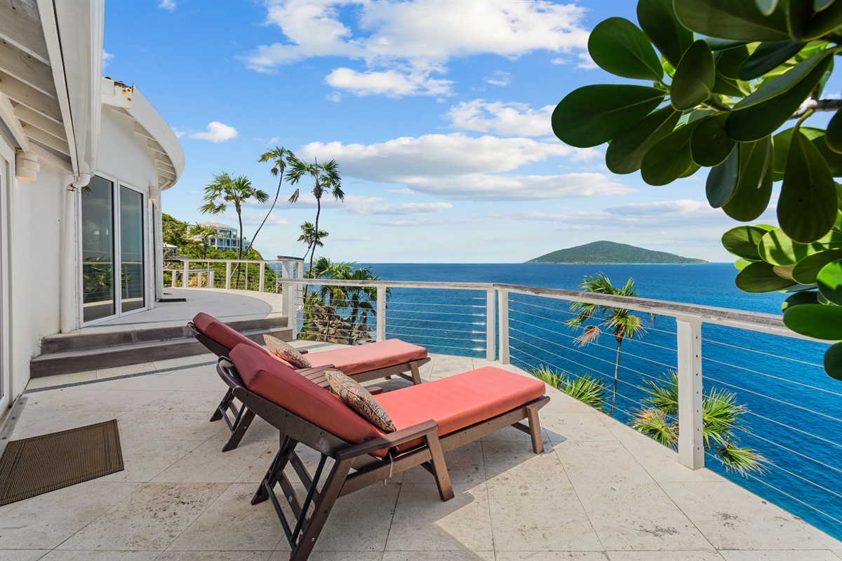 The balcony off of the primary bedroom offers two comfortable lounge chairs to relax in day or night.