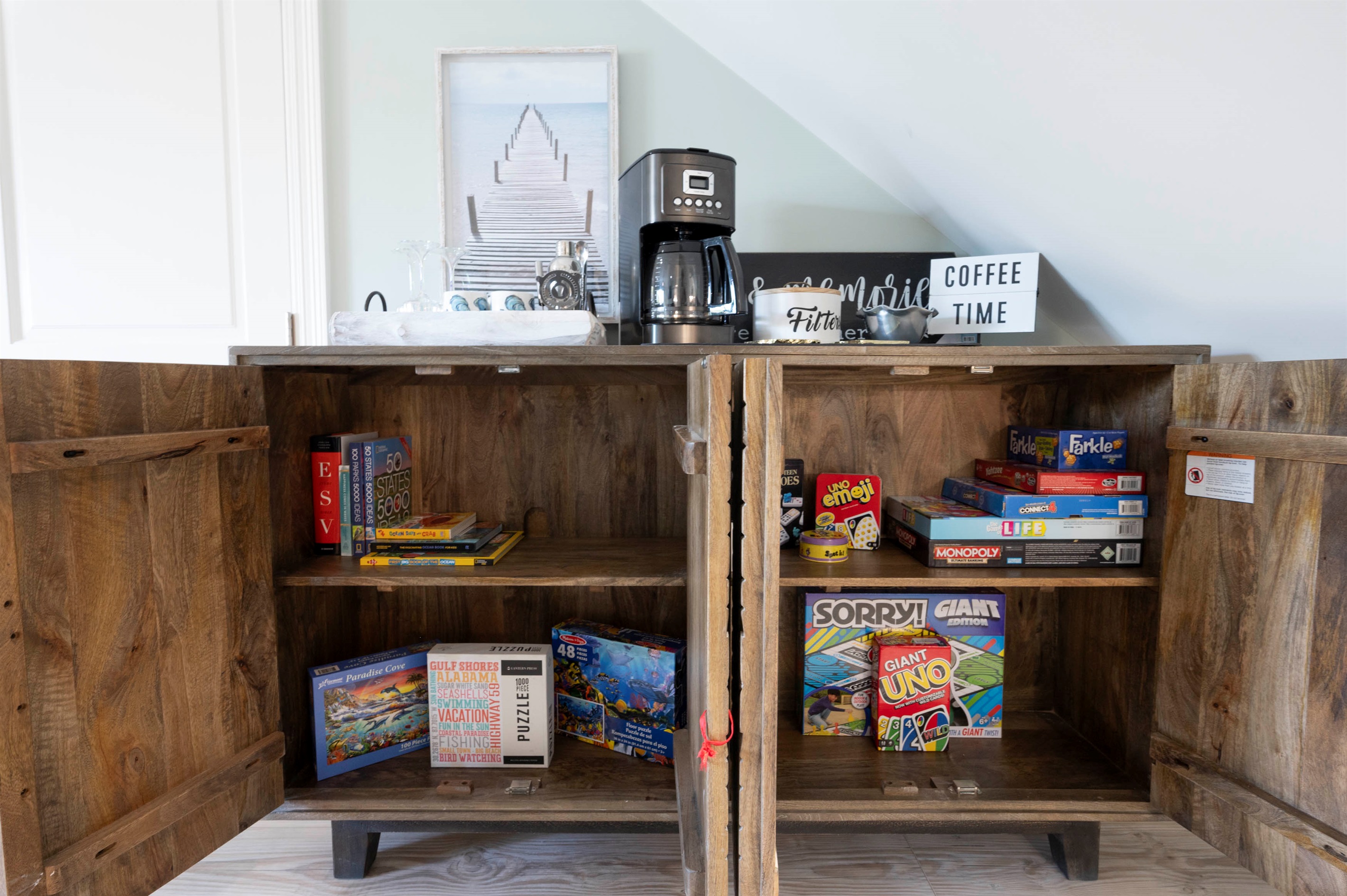 A cozy coffee nook with a cabinet stocked with classic games, puzzles, and books - ideal for rainy afternoons, beach‑day downtime, or playful moments together.
