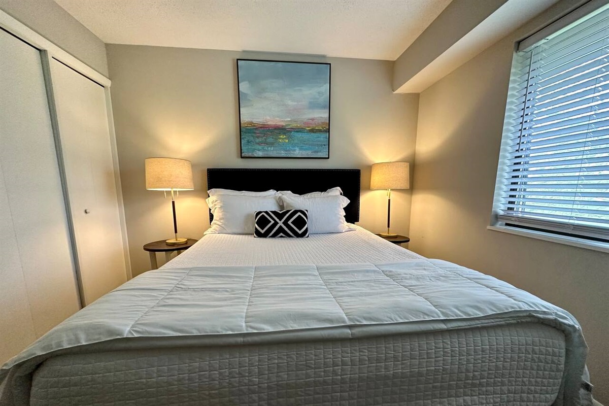 Cozy and peaceful bedroom with a comfortable bed, soft lighting, and room darkening blinds for restful sleep. Stylish modern touches and soothing artwork create a relaxing atmosphere—ideal for unwinding after a busy day or enjoying a quiet morning.