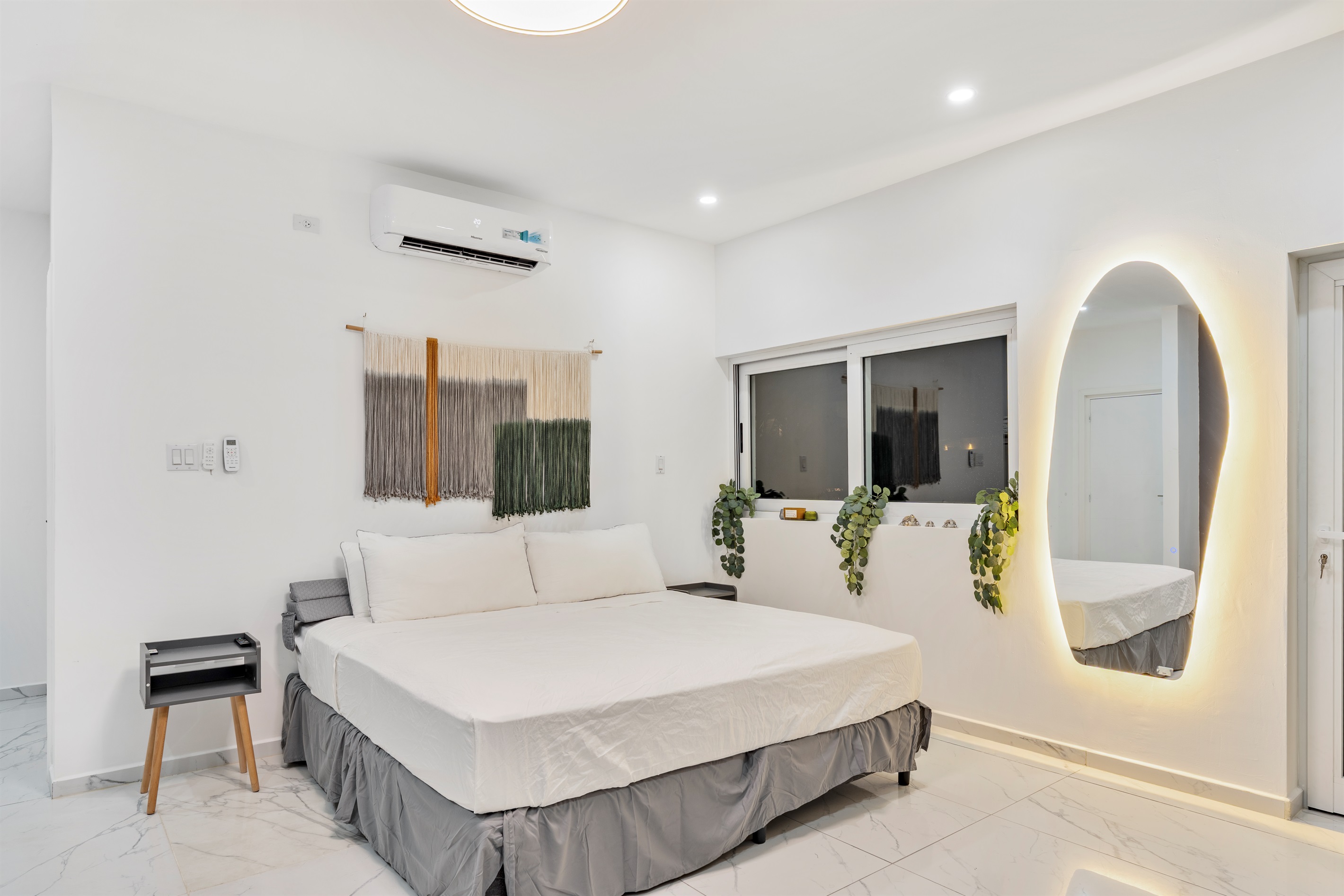 Primary bedroom detail: King bed with LED mirror and greenery on window ledge