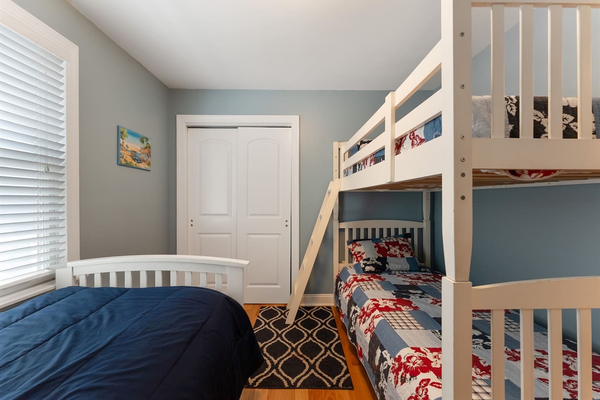 Bedroom features bunk beds and a single bed with a large closet for storage. 