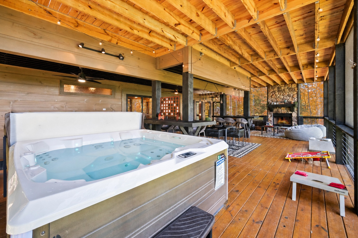 Soak, dine and unwind. This expansive covered deck features a private hot tub, cozy outdoor fireplace, dining space, and games, making it the ultimate mountain hangout spot.