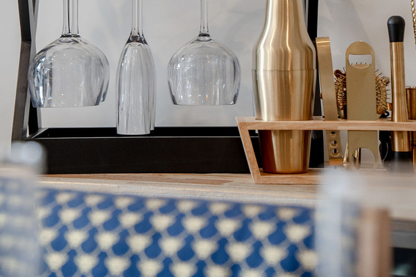The dining sideboard includes hanging glasses and barware, adding a thoughtful entertaining detail close to the table.