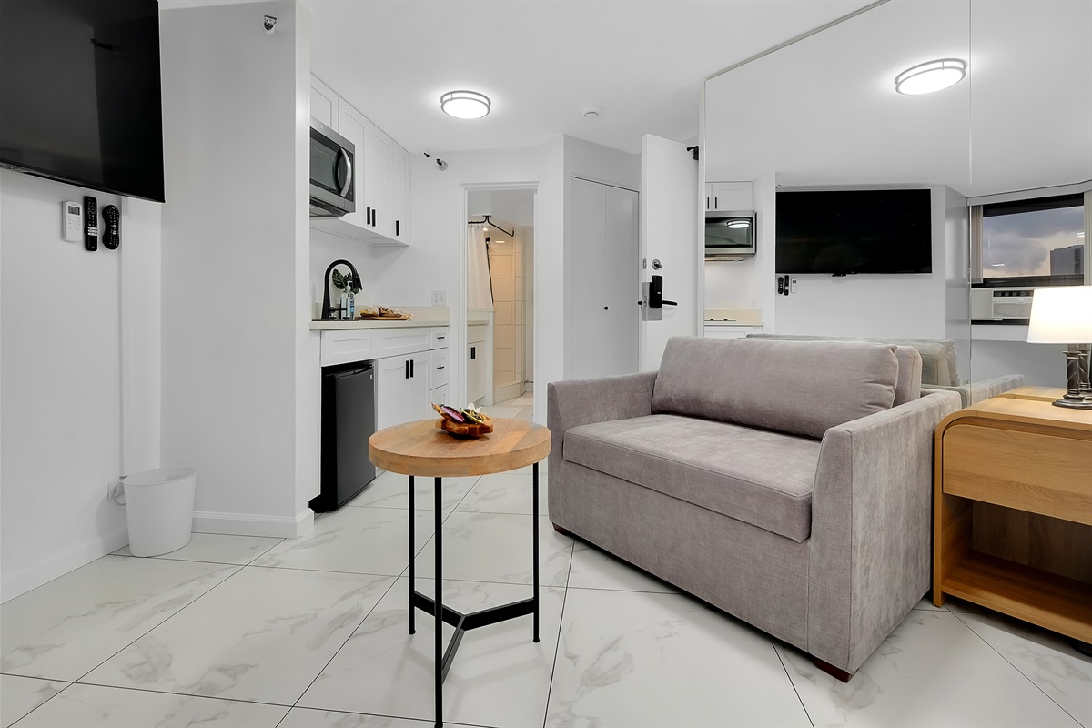 Relax in modern island comfort — this open studio features a cozy sleeper sofa, sleek marble-style floors, and a full kitchenette for your convenience. Thoughtfully designed with a clean, contemporary look, it’s your perfect Waikīkī home base just steps fr