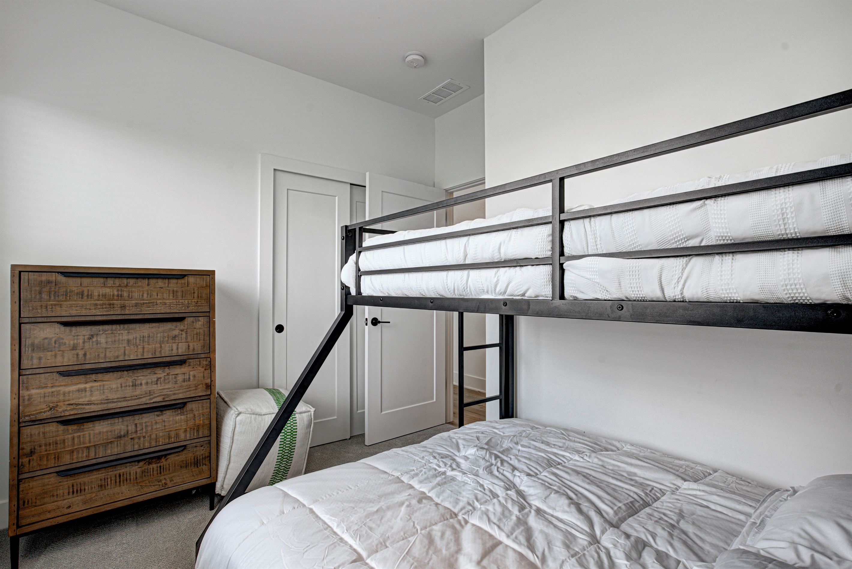 Relax in the serene bedroom featuring a comfortable king-size bed, soft linens, and cozy pillows. Includes nightstands, lamps, walk-in closet, and full-length mirror for added comfort.
