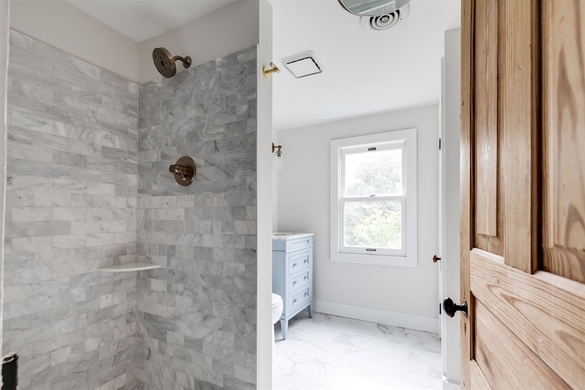 Ensuite Bathroom: Refresh in a sleek shower with marble accents and natural light streaming in!