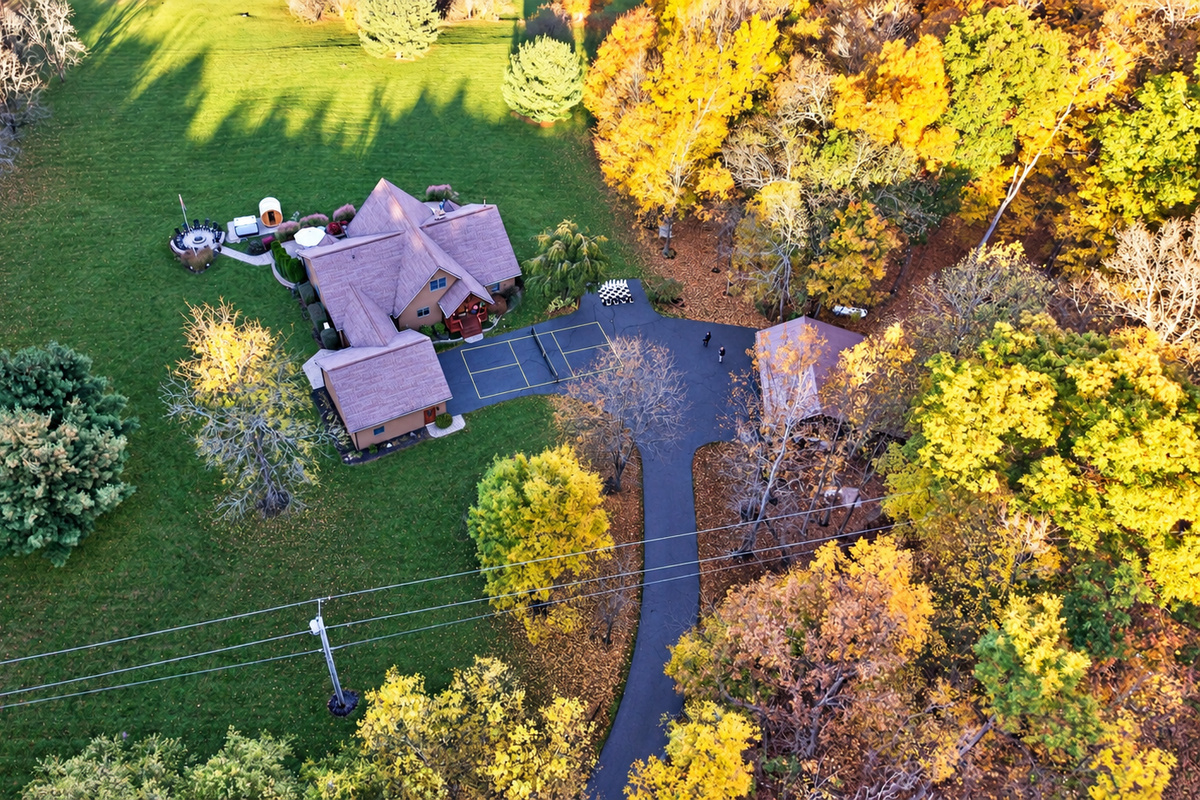 Aerial view of property surrounded by autumn trees